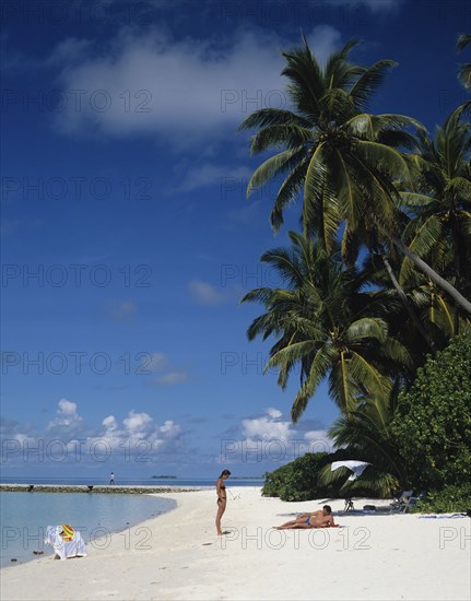 Beach, Maldives. Beach with tourists sunbathing next to the Indian Ocean. Maldives Island Islands Paradise Holiday Sea Water Travel Calm Blue Sky Beach Sand Shore Coast Indian Ocean Asia Asian Palm Trees Clear Vacation Tourists Color Destination Destinations Divehi Rajje Holidaymakers Sand Sandy Beaches Tourism Seaside Shore Tourist Tourists Vacation Sunbather