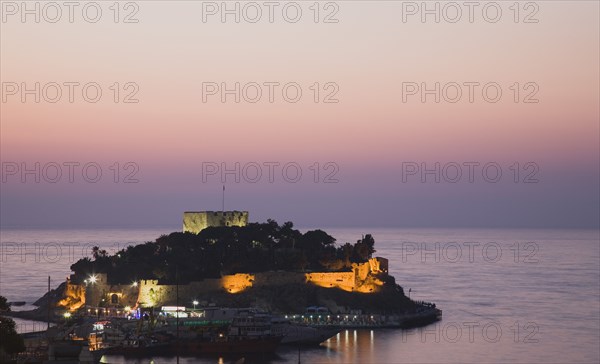 Kusadasi, Aydin Province, Turkey. Sunset over Guvercin Ada the peninsula of Kusadasi also known as Pigeon Island. Turkey Turkish Eurasia Eurasian Europe Asia Turkiye Aydin Province Kusadasi Guvercin Ada Pigeon Island Sunset Sea Water Castle Illuminated Mauve Purple Pink Dusk Castillo Castello Color Destination Destinations European Middle East Nightfall Twilight Evenfall Crespuscle Crespuscule Gloam Gloaming South Eastern Europe Sundown Atmospheric Water Western Asia