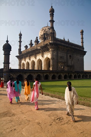 Bijapur, Karnataka, India. Tomb of Ibrahim Rauza with group of young women wearing brightly coloured saris walking in foreground. Adult Adults Ali Rauza Architectural Architecture Asia Back View Bijapur Building Buildings Burial Ground Burial Grounds Cemeteries Cemetery Color Colour Colored Day Daytime Dead Death Five People Full Length Graveyards Group Ibrahim Adil Shah II Ibrahim Rauza India Indian Culture Karnataka Landmark Landmarks National Landmark Outdoors Outside Path Paths People Person Rear View Sari Spiritual Spirituality Tomb Tomb of Ibrahim Rauza Tombs Tourism Tourist Attraction Tourist Attractions Tourist Destination Tourist Destinations Tradition Traditional Traditional Clothes Traditional Clothing Traditions Travel Travel Destination Travel Destinations Vertical Vibrant Color Vibrant Colour Walking Woman Women culture cultures east eastern exotic hindu temple 5 Asian Bharat Classic Classical Cultural Cultures Destination Destinations Female Woman Girl Lady Female Women ...