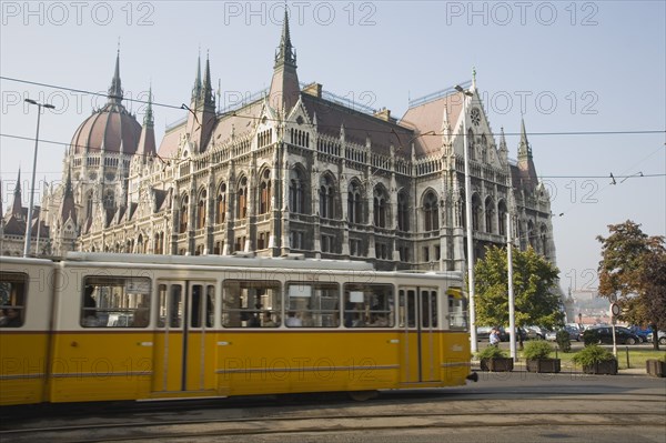Budapest, Pest County, Hungary. Yellow tram passing the Parliament Building. Hungary Hungarian Europe European East Eastern Buda Pest Budapest City Urban Transport Electric Tram Parliament Building Architecture Color Destination Destinations Eastern Europe Parliment