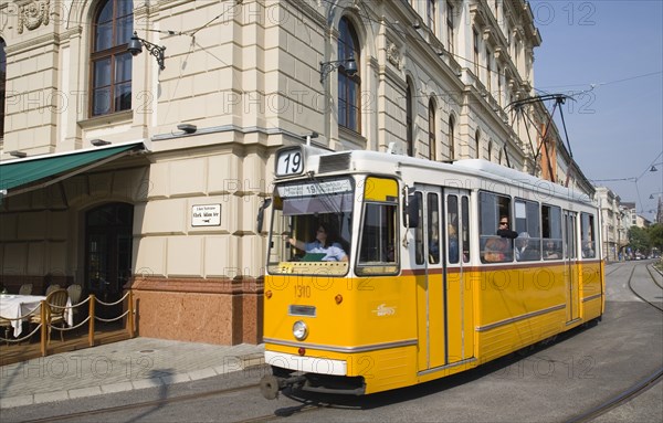 Budapest, Pest County, Hungary. Tram with female driver in street on bank of the River Danube Buda at approach to Chain Bridge. Hungary Hungarian Europe European East Eastern Buda Pest Budapest City Transport Architecture Tram Electric Street Yellow Female Woman Driver Operator Color Destination Destinations Eastern Europe Female Women Girl Lady