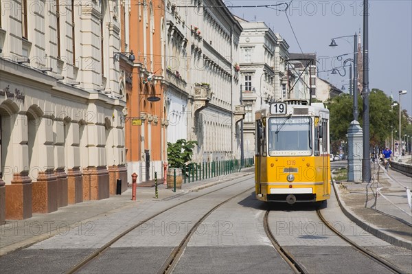 Budapest, Pest County, Hungary. Tram on bank of the River Danube Buda at approach to Chain Bridge. Hungarian Europe European East Eastern Buda Pest Budapest City Architecture Transport Electric Street Tram Yellow Color Destination Destinations Eastern Europe