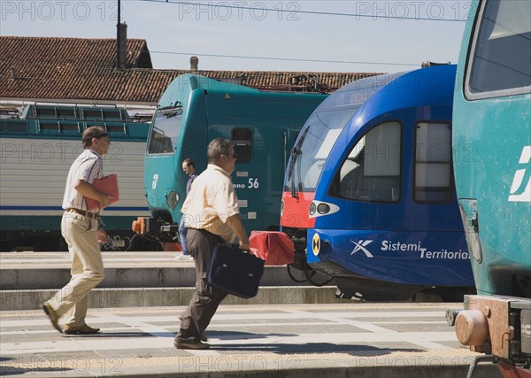Venice, Veneto, Italy. Commuters running to board local train with regional trains on platforms at side. Italy Italia Italian Venice Veneto Venezia Europe European City Transport Train Trains Rail Railways Communications People Travel Commute Commuters Platform Rush Rushing Hurry Station Destination Destinations Southern Europe