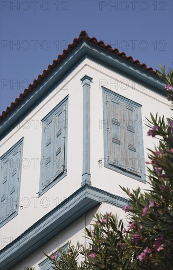 Samos Island, Northern Aegean, Greece. Vathy. Part view of house facade with tiled roof and blue painted wooden window shutters. Greece Greek Europe European Vacation Holiday Holidays Travel Destination Tourism Ellas Hellenic Northern Agean Samos Island Vathy Architecture Detail Exterior Facade Window Shutters Shuttered Closed Color Destination Destinations Ellada Southern Europe