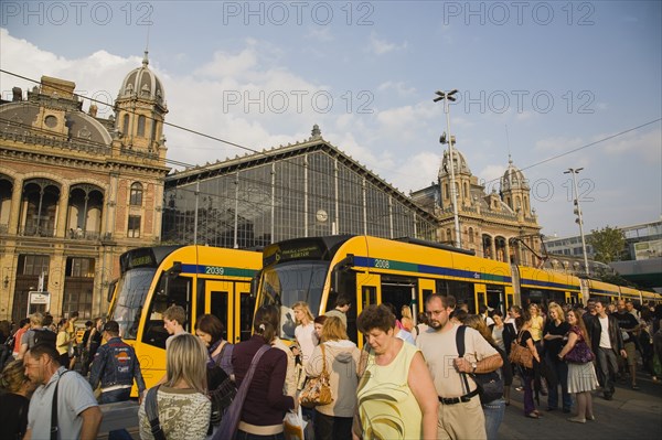 Budapest, Pest County, Hungary. Budapest trams and crowd of passengers in front of rail terminus Budapest Nyugati palyaudvar. Hungary Hungarian Europe European East Eastern Buda Pest Budapest City Transport Rail Train Tram Station Terminus Stop Nyugati Palyaudvar People Crowd Crowded Commuters Tourists Travel Passengers Destination Destinations Eastern Europe Holidaymakers Tourism