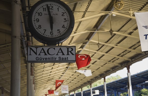 Istanbul, Turkey. Sultanahmet. Station clock on platform giving time of three minutes to six with Turkish flags hanging from roof over platform beyond. Istanbul Sirkeci Terminal or Sirkeci GarA is a terminus main station of the Turkish State Railways or TCDD in Sirkeci on the European part of Istanbul Turkey. International domestic and regional trains running westwards depart from this station which was inaugurated as the terminus of the Orient Express. Turkey Turkish Istanbul Constantinople Stamboul Stambul City Europe European Asia Asian East West Urban Destination Travel Tourism Transportt Rail Railway Train Trains Station Platform Clock Sirkeci TCCD 3 6 Destination Destinations Middle East South Eastern Europe Turkiye Western Asia
