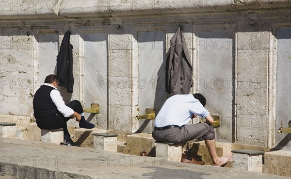 Istanbul, Turkey. Sultanahmet. The New Mosque or Yeni Camii. Two men washing and making ablutions before prayer. Turkey Turkish Istanbul Constantinople Stamboul Stambul City Europe European Asia Asian East West Urban Sultanahmet New mosque Yeni Camii Two 2 Men Male Washing Feet Ablutions Clean Cleaning Destination Destinations Laundry Male Man Guy Middle East Religion Religious South Eastern Europe Turkiye Western Asia