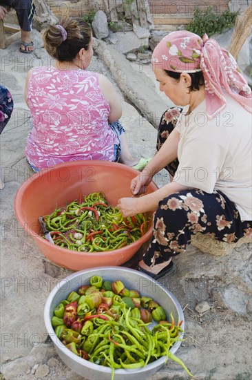 Sirince, Aydin Province, Turkey. Women preparing red and green chilies outside in late afternoon sunshine in the old town. Turkey Turkish Eurasia Eurasian Europe Asia Turkiye Aydin province Sirince Women Female Woman Preparing Chili chilis Chilli Chillis Chillie Chillies Capsicum Capsicums Pepper Peppers Bowl Bowls Color Destination Destinations European Female Woman Girl Lady Female Women Girl Lady Middle East South Eastern Europe Western Asia