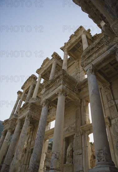Selcuk, Izmir Province, Turkey. Ephesus. Roman Library of Celsus facade angled view looking upwards against clear pale blue sky. Turkey Turkish Eurasia Eurasian Europe Asia Turkiye Izmir Province Selcuk Ephesus Ruin Ruins Roman Library Celcus Column Columns Facde Ancient Architecture Masonry Rock Stone Destination Destinations European History Historic Middle East South Eastern Europe Western Asia