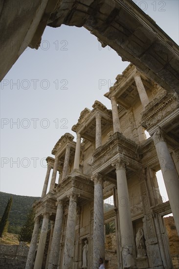 Selcuk, Izmir Province, Turkey. Ephesus. Part view of ornately carved marble facade and archway in antique city of Ephesus on the Aegean sea coast. Turkey Turkish Eurasia Eurasian Europe Asia Turkiye Izmir Province Selcuk Ephesus Ruin Ruins Roman Column Columns Facde Ancient Architecture Masonry Rock Stone Arch Destination Destinations European History Historic Middle East South Eastern Europe Water Western Asia