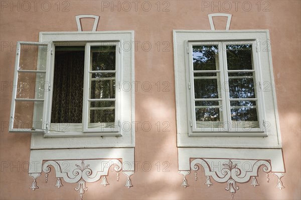 Vienna, Austria. Part view of restored facade of building with pair of windows one open with white frames pink painted walls and trompe loeil effect detail. Austria Austrian Republic Vienna Viennese Wien Europe European City Capital Architecture Facade Window Windows Open Closed Shut Pink Wall Trompe Loeil Detail 1 Color Destination Destinations Osterreich Single unitary Viena Western Europe