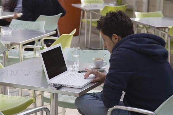 Vienna, Austria. Neubau District. Young man having coffee while surfing the net on laptop at the Museum of Modern Art Museum Moderner Kunst Stiftung Ludwig Wien or MUMOK in the MuseumsQuartier or Museums Quarter. Austria Austrian Republic Vienna Viennese Wien Europe European City Capital Cafe Restaurant Outdoor Outside Table Tables Chair Chairs Man male Coffee Laptop PC Computer Internet Dongle White Bar Bistro Destination Destinations Immature Male Men Guy One individual Solo Lone Solitary Osterreich Surfers Surfer Waves Sport Watersport Breaking Breakers Surfboarding Viena Western Europe