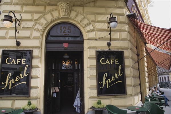 Vienna, Austria. Mariahilf District. Exterior facade of Cafe Sperl frequented by Adolf Hitler. Striped awning pulled out at side with customers sitting at outside tables on street below. Austria Austrian Vienna Viennese Wien Mariahlf 6th District Cafe Sperl Hitler Waitress Entrance Coffee Exterior Europe European Work Urban City Table Tables Schanigarten Bar Bistro Destination Destinations History Historic Osterreich Restaurant Viena Western Europe