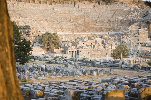 Selcuk, Izmir Province, Turkey. Ephesus. Theatre and ruined buildings in antique city of Ephesus on the Aegean sea coast. Turkey Turkish Eurasia Eurasian Europe Asia Turkiye Izmir Province Selcuk Ephesus Ruin Ruins Roman Amphitheatre Aamphitheater Ancient Architecture Masonry Rock Stone Tourists Destination Destinations European History Historic Holidaymakers Middle East South Eastern Europe Tourism Water Western Asia