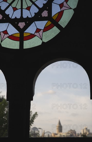 Istanbul, Turkey. Sultanahmet. Part view of dirty stained glass window in Ottoman era waiting room framing view to Galata Tower on Golden Horn. Turkey Turkish Istanbul Constantinople Stamboul Stambul City Europe European Asia Asian East West Urban Destination Travel Tourism Sultanahmet Stainned Glass Window Windows Ottoman Dirty Destination Destinations Middle East South Eastern Europe Turkiye Western Asia