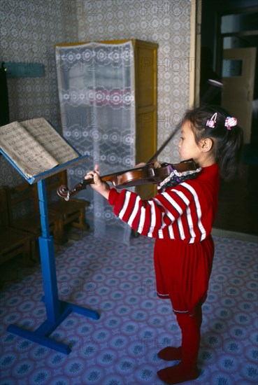 Sariwon, Hwanghae Province, North Korea. Young girl standing in front of music stand playing the violin. Asia Asian Daehanminguk Hanguk Immature Kids Korean Northern One individual Solo Lone Solitary 1 Single unitary