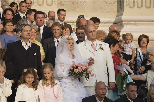 Budapest, Pest County, Hungary. Bride and groom with wedding guests pose for photographs on steps of Saint Stephens Basilica after service Hungary Hungarian Europe European East Eastern Buda Pest Budapest City People Crowd Couple Wed Wedding Marriage Bride Groom White Dress Veil Flowers St Saint Stephen Stephens Basilica Church Exterior Color Cultural Cultures Eastern Europe Marriage Marrying Espousing Hymeneals Nuptials Order Fellowship Guild Club Religion Religious