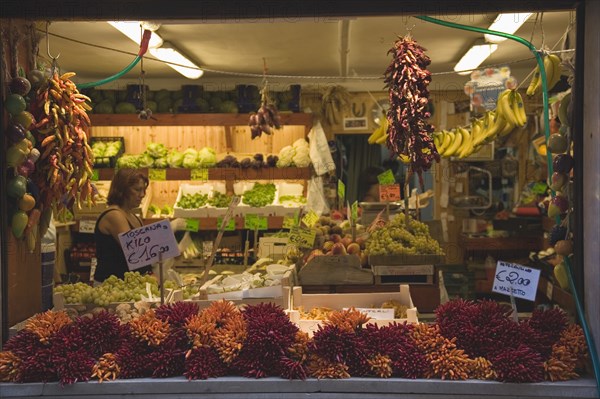 Venice, Veneto, Italy. Italy Veneto Venice Centro Storico Local grocer with display of fresh fruit vegetables and chillies. Woman in interior. Italy Italia Italian Venice Veneto Venezia Europe European City Centro Storico Grocer Grocers Grocery Vegetables Fruit Store Shop Customer Chili Chilli Chillies Chillis Pepper Peppers Woman Destination Destinations Female Women Girl Lady Southern Europe