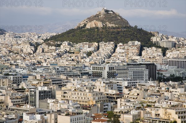 Athens, Attica, Greece. Mount Lycabettus rising in central Athens with densely populated city below. Greece Greek Europe European Vacation Holiday Holidays Travel Destination Tourism Ellas Hellenic Attica Athens City View Aerial Cityscape Elevated Houses Housing Mount Lycabettus Atenas Athenes Destination Destinations Ellada Southern Europe