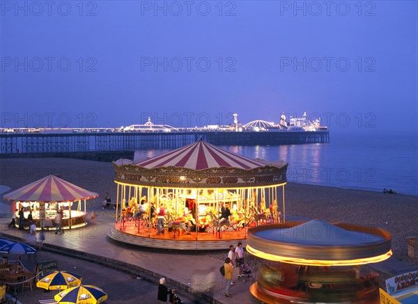 Brighton, East Sussex, England. Seafront amusements and Brighton Pier illuminated at night. Great Britain Nite Northern Europe UK United Kingdom