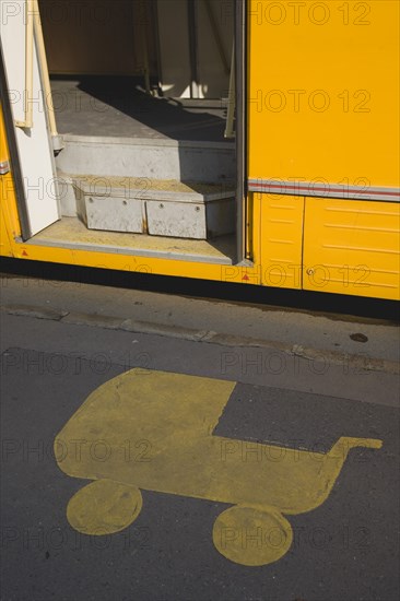 Budapest, Pest County, Hungary. Painted marking on pavement at tram stop depicting pram with open door of tram stopped beside it. Hungary Hungarian Europe European East Eastern Buda Pest Budapest City Urban Transport Tram Neo Yellow Sign Pram Babycot Stroller Painted Ground Pavement Sidewalk Eastern Europe Signs Display Posted Signage