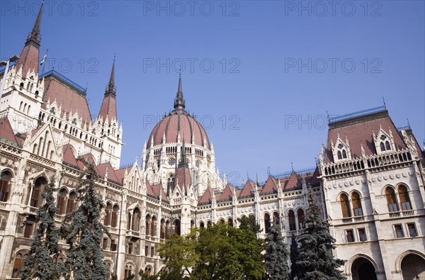 Budapest, Pest County, Hungary. Neo-Gothic exterior of the Parliament Building with central dome built between 1896 and 1904. Hungary Hungarian Europe European East Eastern Buda Pest Budapest City Urban Neo Gothic Parliament Building Architecture Exterior Facade Blue Sky Destination Destinations Eastern Europe Parliment