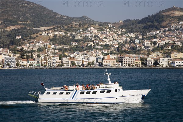 Samos, Northern Aegean, Greece. Vathy. Ferry between Samos and Kusadasi in Turkey as it leaves Vathy with town houses spread out across hillside beyond. Greece Greek Europe European Vacation Holiday Holidays Travel Destination Tourism Ellas Hellenic Transport Ferry Boat Transport Ferry Boat Ship Water Sea Hills Harbour Harbor Houses Housing Destination Destinations Ellada Middle East South Eastern Europe Southern Europe Turkish Turkiye Water Western Asia