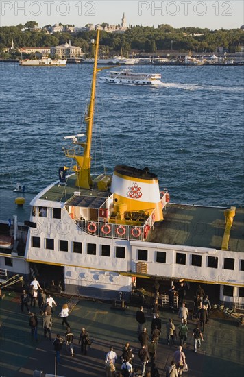 Istanbul, Turkey. Sultanahmet Bosphorous passenger ferry at sunset with people boarding. Turkey Turkish Istanbul Constantinople Stamboul Stambul City Europe European Asia Asian East West Urban Destination Travel Tourism Sultanahmet Bosphorous Passenger Passengers Ferry Boat Ship Transport Water Sea Commute Commuters Destination Destinations Middle East South Eastern Europe Sundown Atmospheric Turkiye Water Western Asia