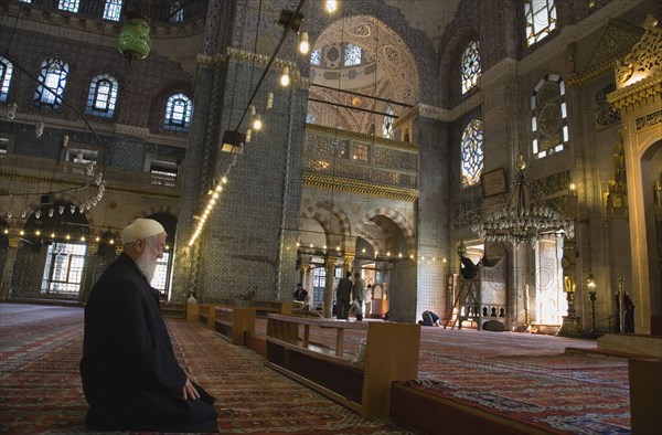 Istanbul, Turkey. Sultanahmet. The New Mosque or Yeni Camii. Tiled and highly decorated interior with elderly man kneeling in worship performing salah or prayer. Turkey Turkish Istanbul Constantinople Stamboul Stambul City Europe European Asia Asian East West Urban Destination Travel Tourism Sultanahmet New Mosque Yeni Camii Interior Muslim Moslem Islam Islamic Religion Religious Worshipping Salah Man Worship Destination Destinations Male Men Guy Middle East Old Senior Aged One individual Solo Lone Solitary Performance Religion Religious Muslims Islam Islamic South Eastern Europe Turkiye Western Asia