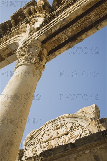 Selcuk, Izmir Province, Turkey. Ephesus. Detail of carved archway supporting column and wall relief in antique city of Ephesus on the Aegean sea coast. Turkey Turkish Eurasia Eurasian Europe Asia Turkiye Izmir Province Selcuk Ephesus Ruin Ruins Roman Column Columns Facde Ancient Architecture Masonry Rock Stone Arch Blue Destination Destinations European History Historic Middle East South Eastern Europe Water Western Asia