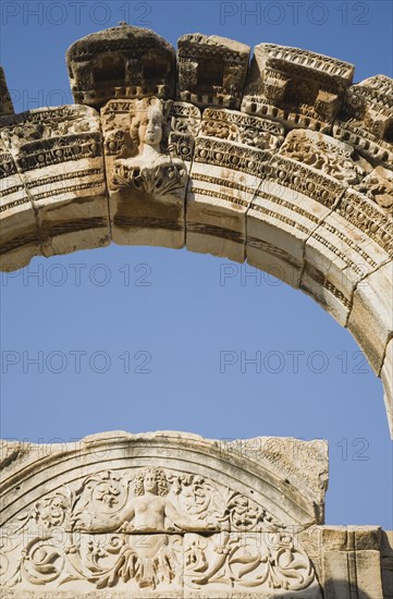 Selcuk, Izmir Province, Turkey. Ephesus. Detail of carved archway and wall relief against clear blue sky in ancient city of Ephesus on the Aegean sea coast. Turkey Turkish Eurasia Eurasian Europe Asia Turkiye Izmir Province Selcuk Ephesus Ruin Ruins Roman Column Columns Facde Ancient Architecture Masonry Rock Stone Arch Destination Destinations European History Historic Middle East South Eastern Europe Water Western Asia