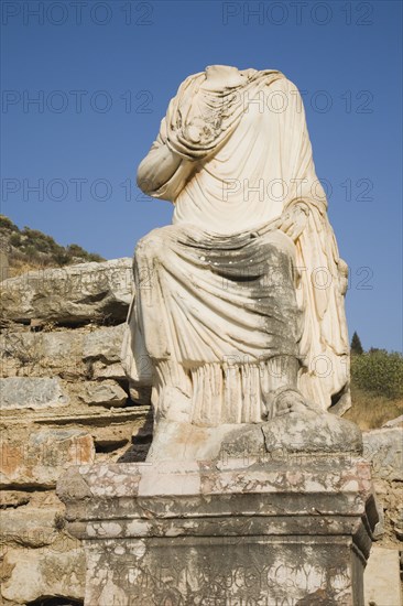 Selcuk, Izmir Province, Turkey. Ephesus. Headless statue on plinth in ancient city of Ephesus on the Aegean sea coast. Turkey Turkish Eurasia Eurasian Europe Asia Turkiye Izmir Province Selcuk Ephesus Ruin Ruins Roman Column Columns Facde Ancient Architecture Masonry Rock Stone Statue Headless Destination Destinations European History Historic Middle East South Eastern Europe Water Western Asia