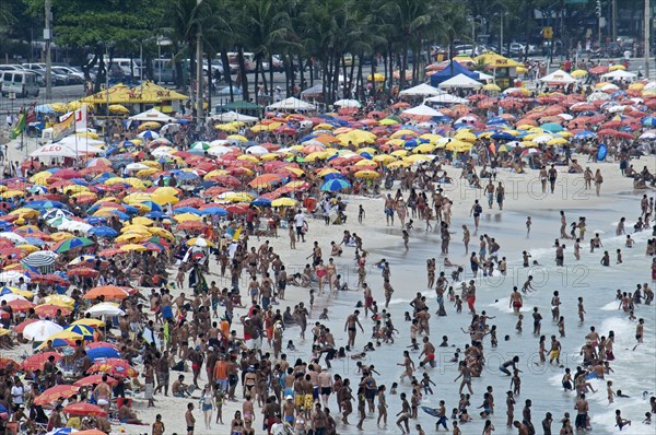 Rio de Janeiro, Brazil. Copacabana beach. Crowds on the beach and in the sea bikinis and multi-coloured beach umbrellas. Brazil Brasil Brazilian Brasilian South America Latin Latino American City Travel Destination Urban Vacation Beach Beaches People Sunbathing Crowds Rio de Janeiro Copacabana Umbrellas Parasols Destination Destinations Holidaymakers Latin America Sand Sandy Beach Tourism Seaside Shore Tourist Tourists Vacation Sand Sandy Beaches Tourism Seaside Shore Tourist Tourists Vacation South America Southern Sunbather Water