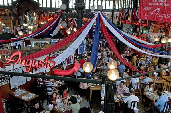 Santiago, Chile. Seafood restaurant section of Central Market with diners at tables eating under red white and blue hanging decorations. Chile Chilean South America American Hispanic Santiago City Cityscape Urban Travel Destination Vacation Holiday Mercado Central Market Retaurant Cafe Seafood Fish View Over Diners People Crowded Tables Eating Food Drink Bunting Streamers Bar Bistro Destination Destinations Latin America Latino South America Southern