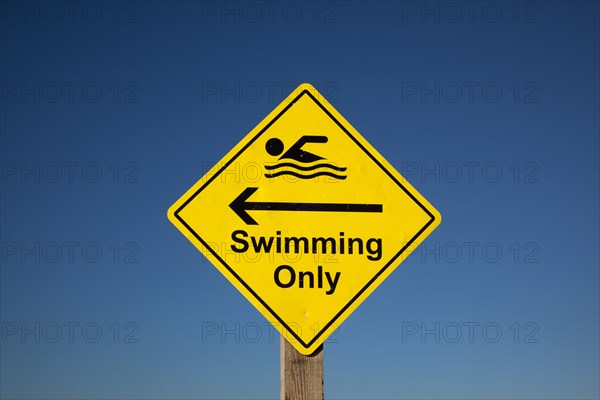 Sign indicating stretch of beach suitable for safe swimming. Sign Signs Information Warn Warning Indicate Indicating Safe Safety Yellow Blue Sky Swim Swimming Swimmer Swimmers Show Showing Point Pointing Arrow Post Only