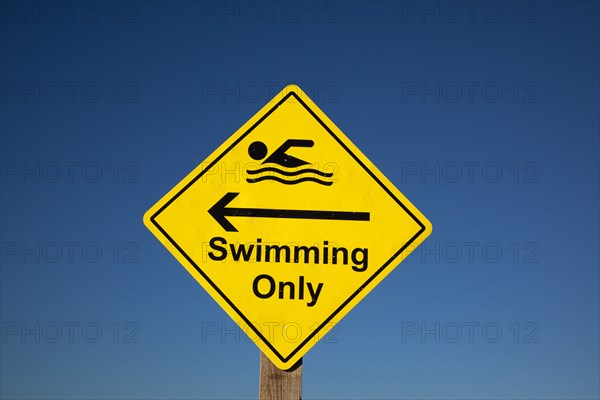 Shoreham-by-Sea, West Sussex, England. Sign indicating stretch of beach suitable for safe swimming. Sign Signs Information Warn Warning Indicate Indicating Safe Safety Yellow Blue Sky Swim Swimming Swimmer Swimmers Show Showing Point Pointing Arrow Post Only