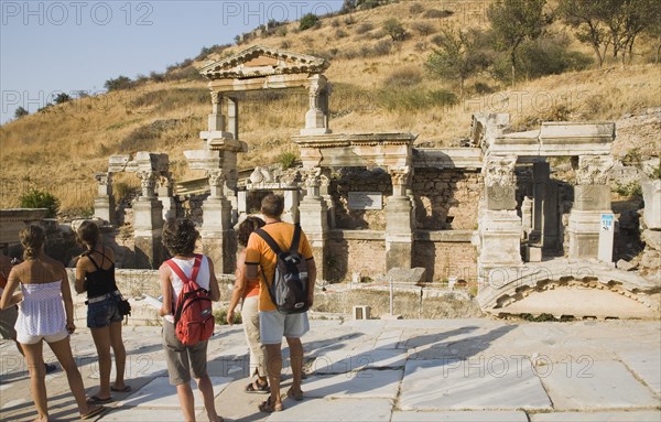 Selcuk, Izmir Province, Turkey. Ephesus. Tourists stopped to look at ruined stonework in ancient city of Ephesus on the Aegean sea coast. Turkey Turkish Eurasia Eurasian Europe Asia Turkiye Izmir Province Selcuk Ephesus Ruin Ruins Roman Column Columns Facde Ancient Architecture Masonry Rock Stone Tourist Tourists Destination Destinations European History Historic Holidaymakers Middle East Sightseeing South Eastern Europe Tourism Water Western Asia