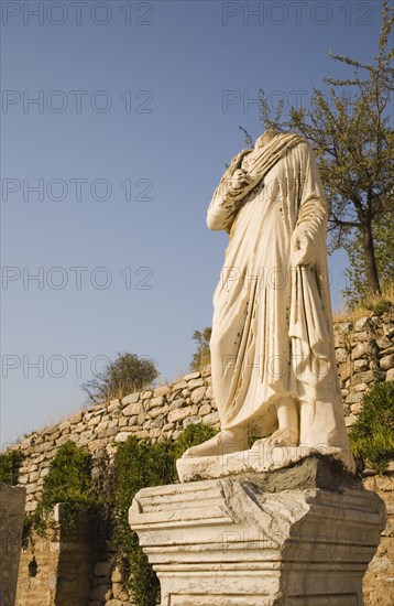 Selcuk, Izmir Province, Turkey. Ephesus. Headless statue on plinth in ancient city of Ephesus on the Aegean sea coast. Turkey Turkish Eurasia Eurasian Europe Asia Turkiye Izmir Province Selcuk Ephesus Ruin Ruins Roman Column Columns Facde Ancient Architecture Masonry Rock Stone Headless Statue Destination Destinations European History Historic Middle East South Eastern Europe Water Western Asia