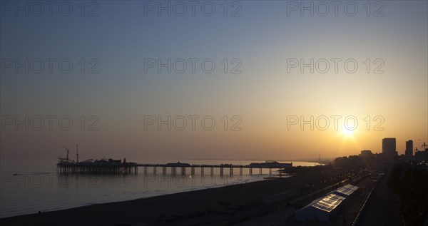 Brighton, East Sussex, England. View of the pier at sunset from the seafront promenade in Kemptown. England English UK United Kingdom United Kingdom GB Great Great Britain Britain British Europe European East Sussex East Sussex County Brighton Kemptown Marine Parade Sea Seafront Promenade Pier Sunet Blue Sky Illuminated Lit up Travel Silhouette Silhouetted