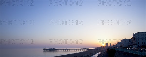 Brighton, East Sussex, England. View of the pier at sunset from the seafront promenade in Kemptown. England English UK United Kingdom United Kingdom GB Great Great Britain Britain British Europe European East Sussex East Sussex County Brighton Kemptown Marine Parade Sea Seafront Promenade Pier Sunet Blue Sky Illuminated Lit up Travel Silhouette Silhouetted