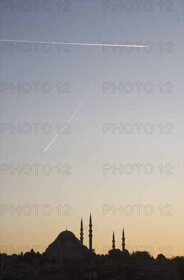 Istanbul, Turkey. Sultanahmet. Suleymaniye Mosque silhouetted against pale sunset sky with aircraft contrails high above. Turkey Turkish Istanbul Constantinople Stamboul Stambul City Europe European Asia Asian East West Urban Destination Travel Tourism Sultanahmet Suleymaniye Mosque Minarets Sunset Silhouette Silhouetted Contrails Condensation Trail Trails Sky Aircraft Planes Airplane Aeroplane Blue Destination Destinations Middle East Religion Religious Solid Outline Shade Silhouette Solid Outline Shade Silhouetted South Eastern Europe Sundown Atmospheric Turkiye Western Asia