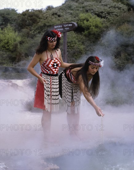 Rotorua, North Island, New Zealand. Thermal Pools with Maori girls in traditional dress. New Zealand Zealander Zealanders Australasia North Island Rotorua Geothermal Thermal Lake Geography Geographic Feature Hot Pool Pools Water Spring Springs Lake Ethinic Traditional Culture Steam Tourism Tuatara Travel Maori Women Woman Girl Girls Dress Attire Costume Costumes Antipodean Classic Classical Cultural Cultures Destination Destinations Female Woman Girl Lady Female Women Girl Lady Historical Immature Northern Oceania Older History Historic Young