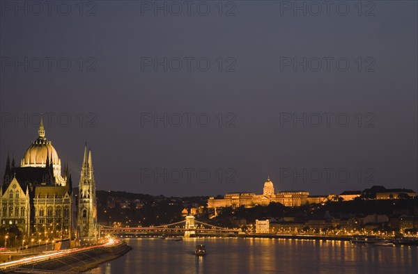 Budapest, Hungary. View along the River Danube at night with the Parliament building on the left the Chain Bridge and the Royal Palace on the right all illuminated brightly. Hungary Hungarian Europe European East Eastern City Cityscape Skyline Night Nighttime Dark Lights Lit Illuminated River Danube Parliament Royal Palace Chain Bridge Travel Destination Holiday Vacation Break Buda Pest Budapest Citiscape Building Buildings Urban Architecture Destination Destinations Eastern Europe Nite Parliment