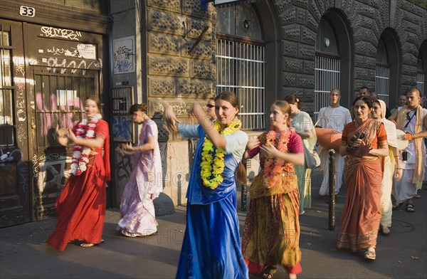 Budapest, Pest County, Hungary. Hare Krishna devotees singing and dancing on Andrassy UtIn Pest with graffiti covered doorway behind. The International Society for Krishna Consciousness or ISKCON also known as the Hare Krishna movement is a Hindu Vaishnava religious organization. Hungary Hungarian Europe European East Eastern Buda Pest Budapest City Religion religious Hare Krishna Hindu Hinduism Vaishnava Women Women Female Worship Worhippers Dance Dancing Dancers Sing Singing Eastern Europe Female Woman Girl Lady Order Fellowship Guild Club Religion Religious Hinduism Hindus