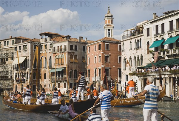 Venice, Veneto, Italy. Participants in the Regata Storico historical Regatta held annually in September approaching the Rialto bridge with onlookers gathered on the balconies of canalside buildings behind. Teams represent Sestiere districts of Venice in traditional races. Italy Italia Italian Venice Veneto Venezia Europe European City Regata Regatta Gondola Gondola Gondolas Gondolier Boat Architecture Exterior Water Classic Classical Destination Destinations History Historic Holidaymakers Older Southern Europe Tourism Tourist