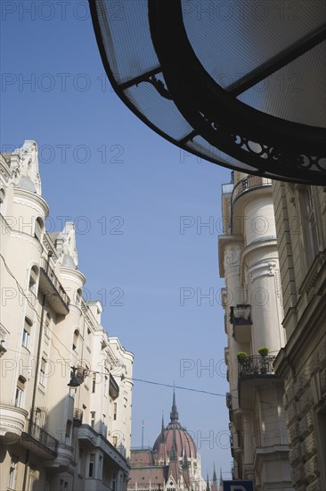 Budapest, Pest County, Hungary. Art Nouveau era apartment facades with view towards the Hungarian Parliament Building behind. Hungary Hungarian Europe European East Eastern Buda Pest Budapest City Architecture Apartment Flats Building Building Buildings Exterior Facade Parliament Art Nouveau Neo Gothic Blue Destination Destinations Eastern Europe Flat Parliment