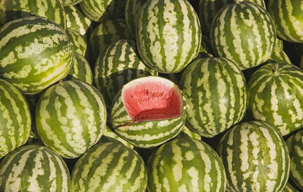 Kusadasi, Aydin Province, Turkey. Fresh watermelon on sale at town produce market with central fruit cut open to show red flesh and seeds. Turkey Turkish Eurasia Eurasian Europe Asia Turkiye Aydin Province Kusadasi Market Fruit Display Melon Watermelon Water Melons Watermelons Green Yello Red Pattern Color Destination Destinations European Middle East South Eastern Europe Western Asia