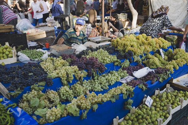 Kusadasi, Aydin Province, Turkey. Stall with display of grapes figs beans and chilies for sale in busy market. Asian Color Destination Destinations European Middle East South Eastern Europe Turkish Turkiye Western Asia