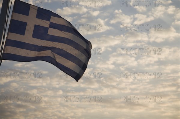 Samos, Northern Aegean, Greece. Greek flag flying from ferry between Samos and Kusadasi in Turkey as it leaves Vathy in Samos with silvery cloud in evening sky behind. Greece Greek Europe European Vacation Holiday Holidays Travel Destination Tourism Ellas Hellenic Flag Sky Clouds Blue Clouds Cloud Sky Color Destination Destinations Ellada Middle East South Eastern Europe Southern Europe Sundown Atmospheric Turkish Turkiye Warm Light Western Asia White