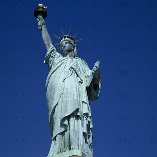New York, New York State, USA. Statue of Liberty. Close view of figure and torch against a bright blue sky. American Color Destination Destinations North America Northern United States of America